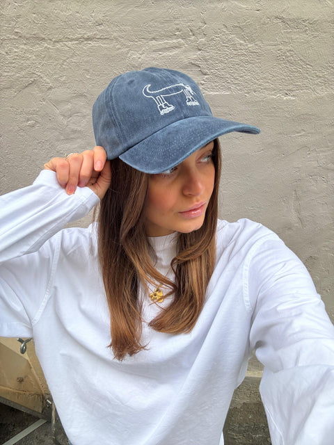Girl wearing a blue cap with  the BERT Coffee & Matcha crocodile.